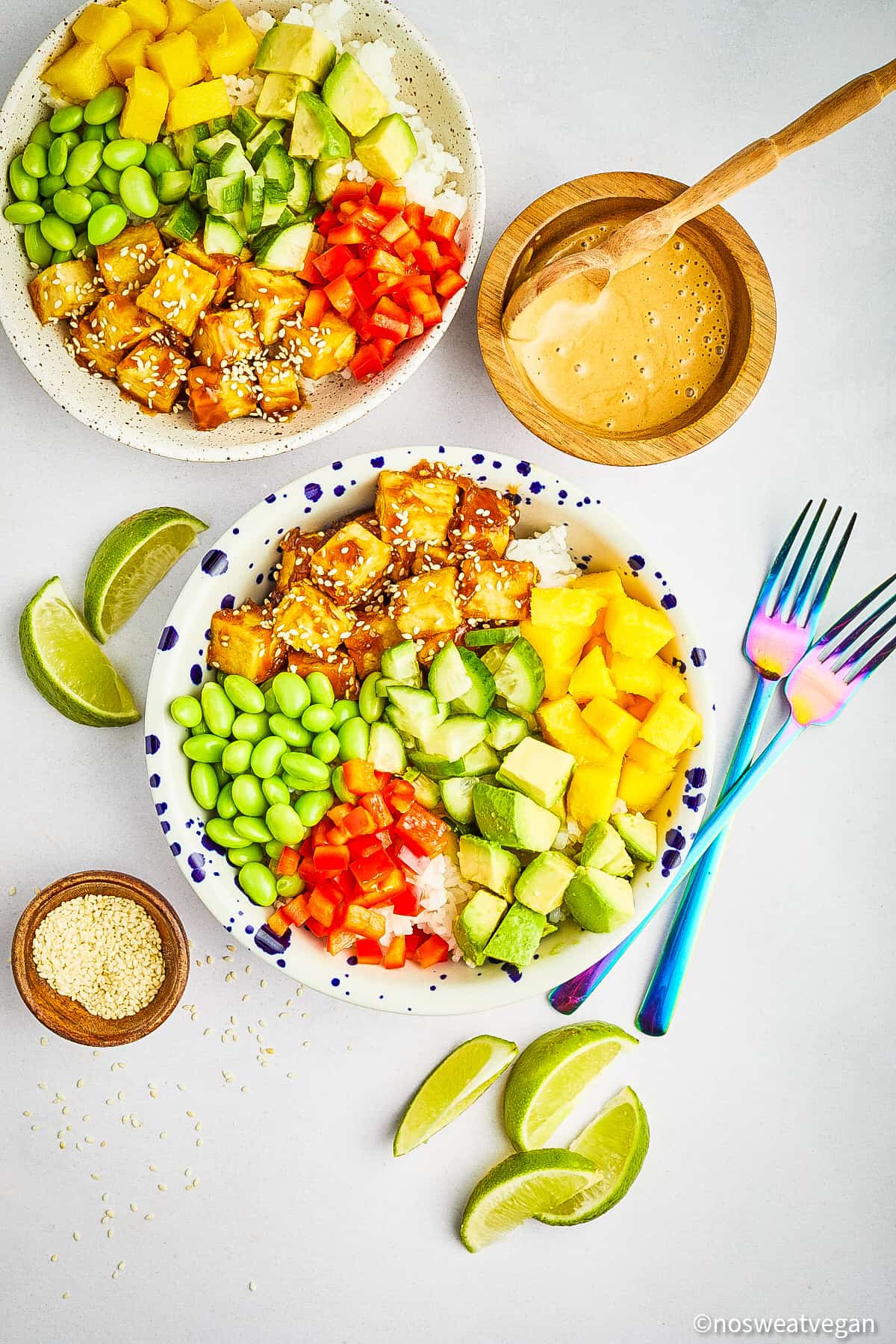 Two vegan poke bowls next to a bowl with ginger tahini sauce.