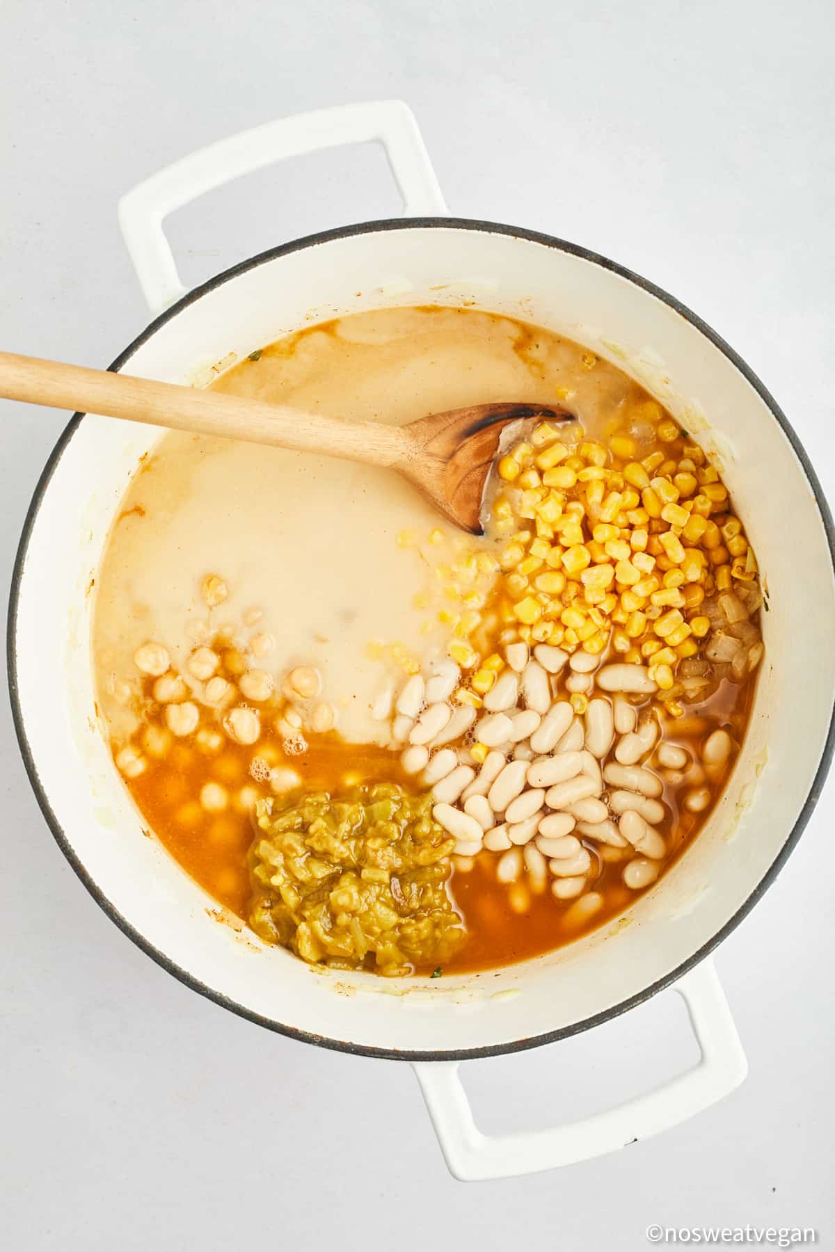Chickpeas, corn, white beans, chilis, and veggie broth in a pot.