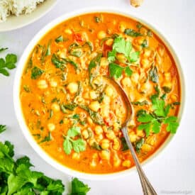 Bowl of chickpea and spinach curry with a spoon.
