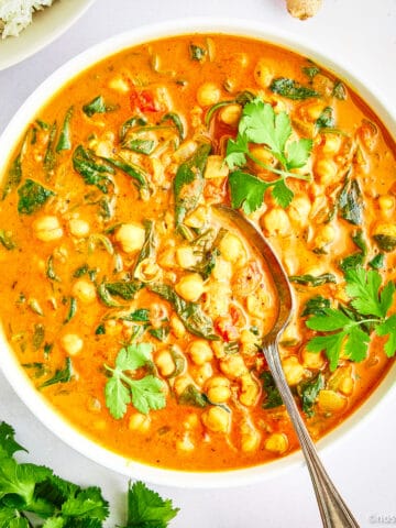 Bowl of chickpea and spinach curry with a spoon.