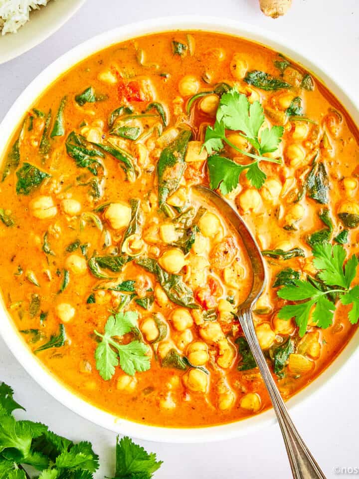 Bowl of chickpea and spinach curry with a spoon.