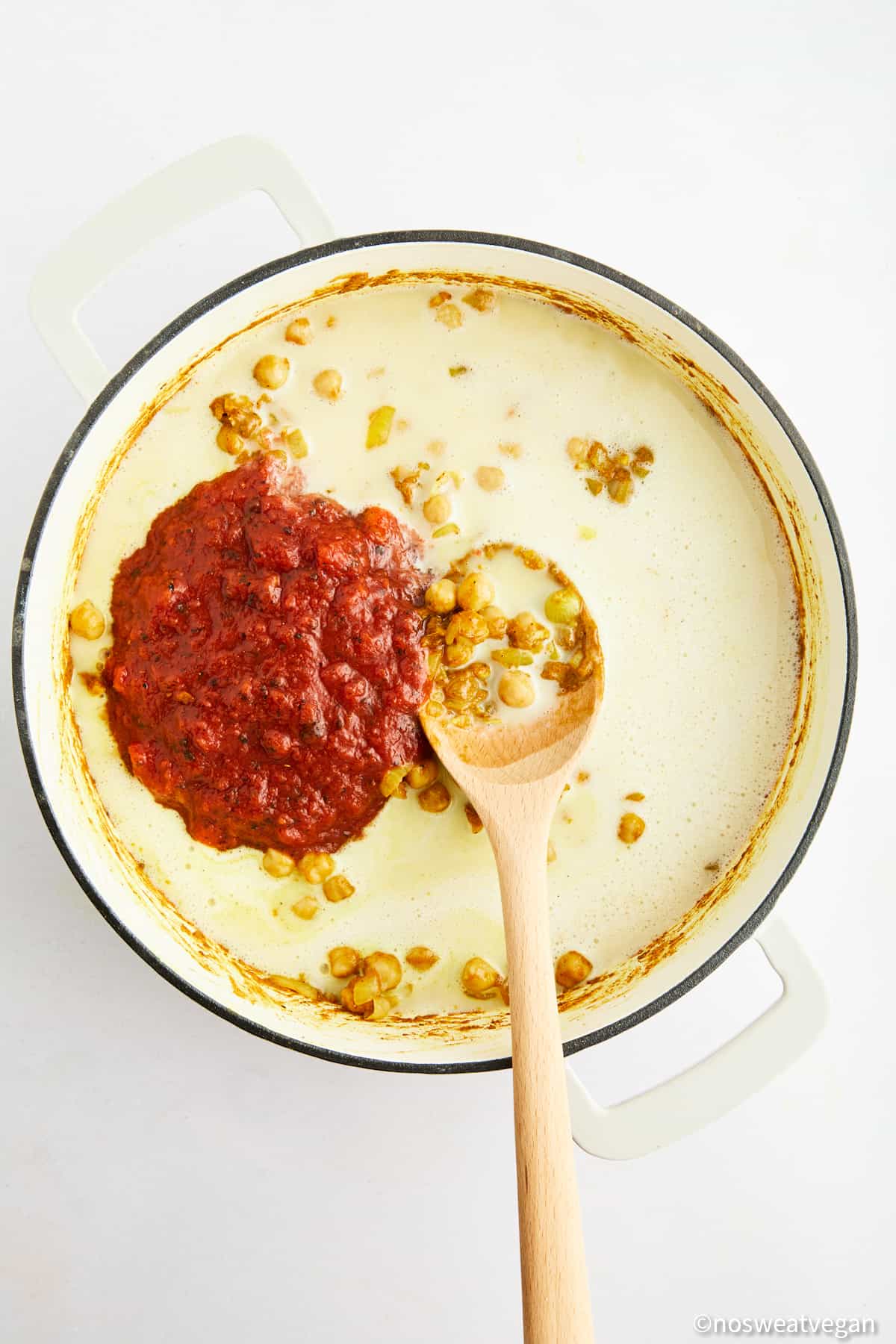 Adding tomatoes and coconut milk to curry.