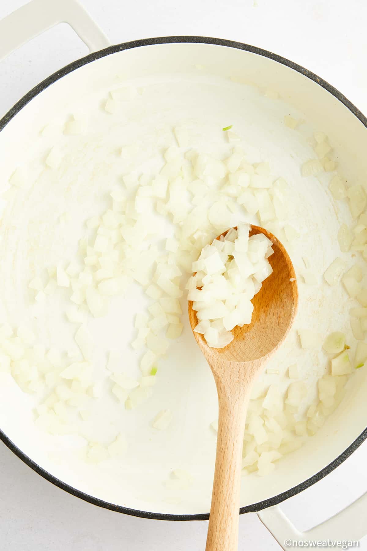 Cooked onion in a pot with a spoon.