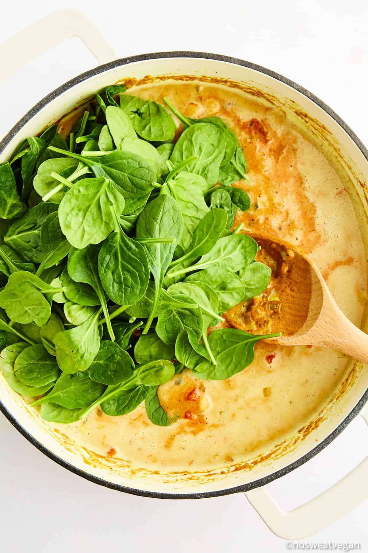 Adding spinach to curry.