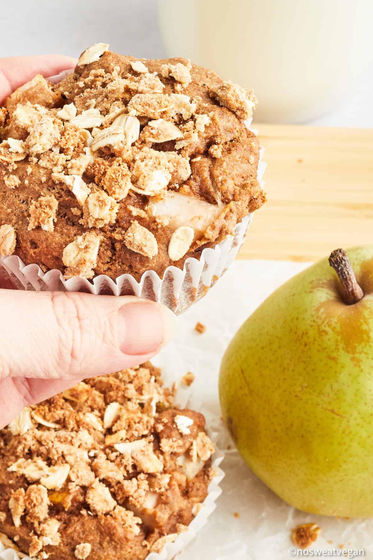Hand picking up a pear muffin.