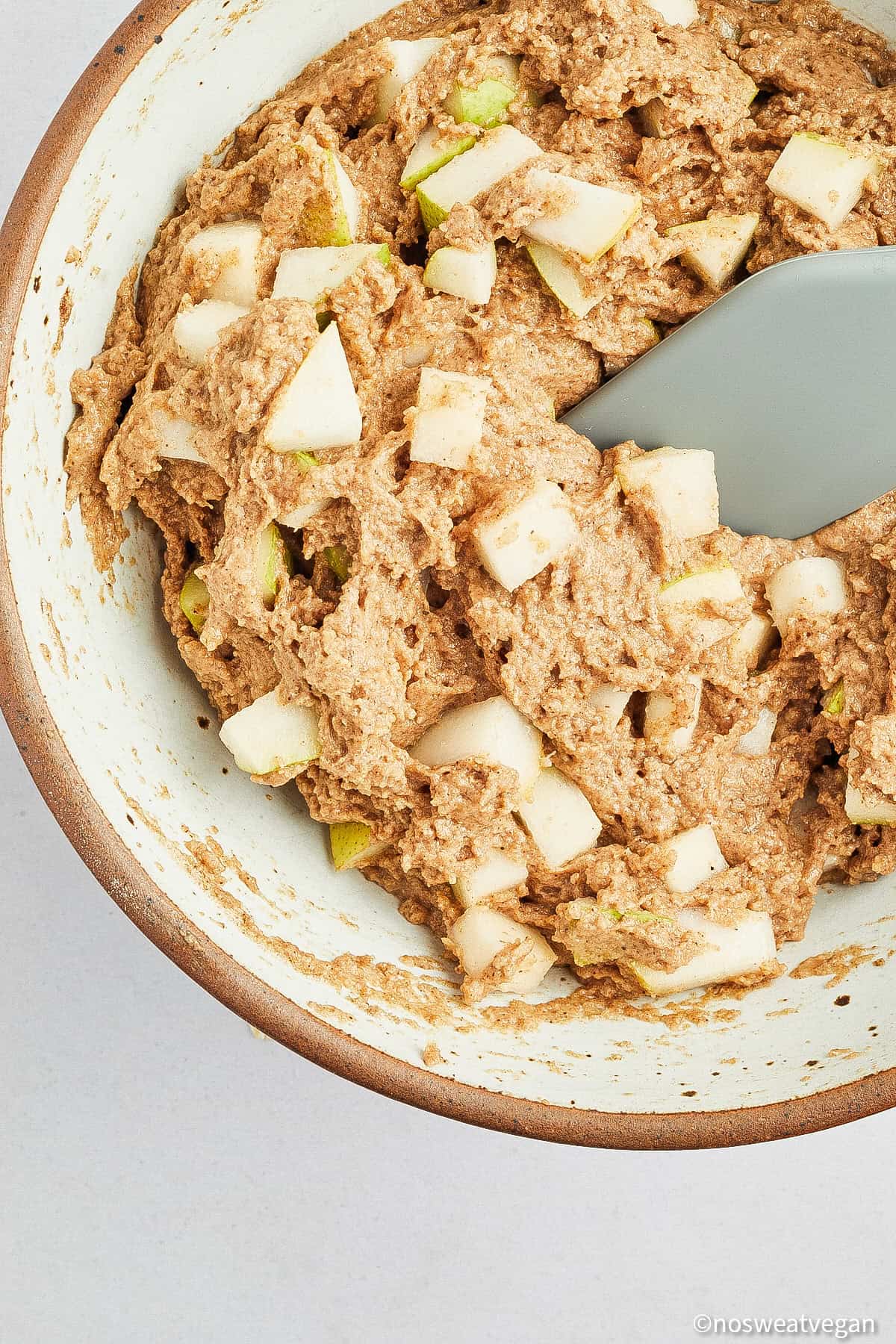 Muffin batter in a bowl with pear cubes.