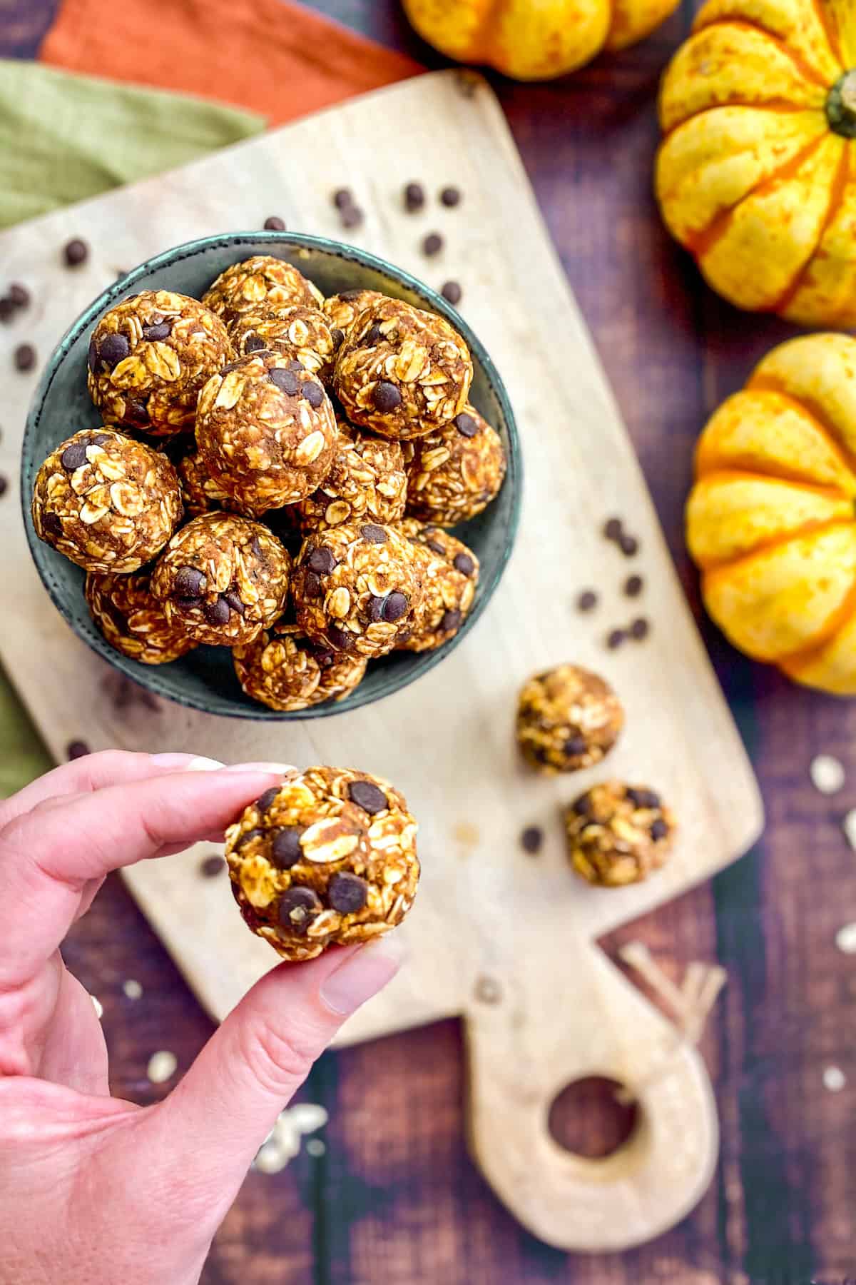 Hand picking up a pumpkin bite from a bowl on a cutting board.