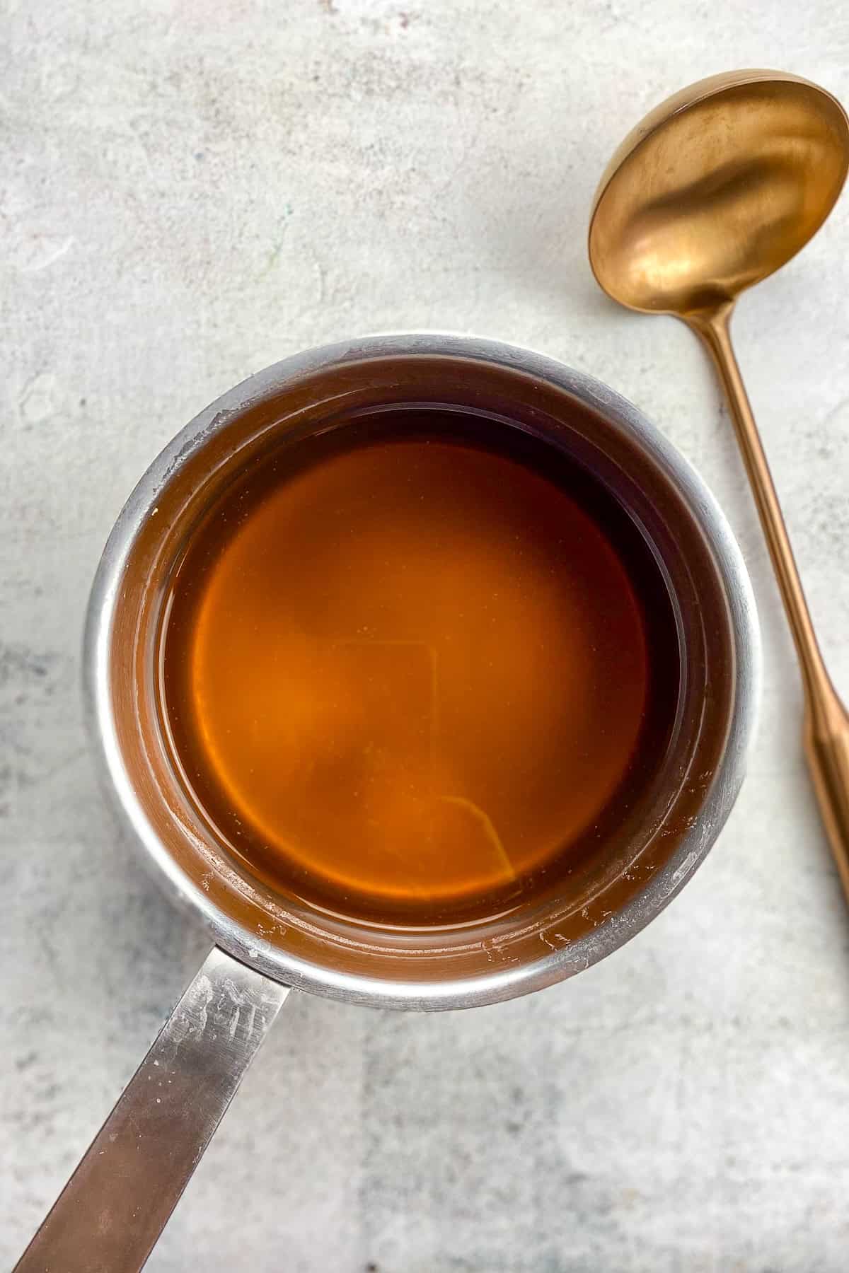 Broth in a pot next to a ladle.