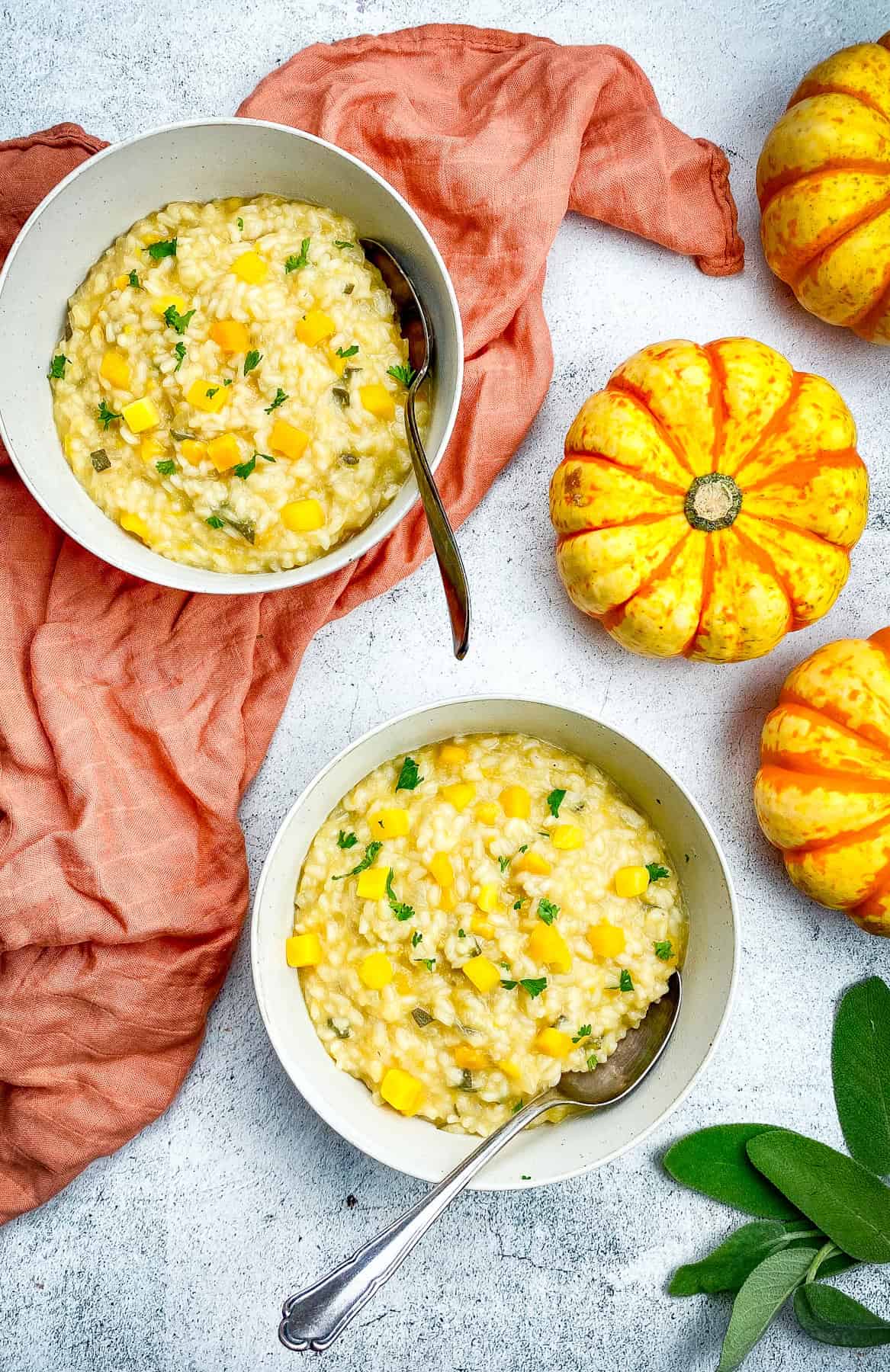 Two bowls of vegan risotto next to pumpkins.