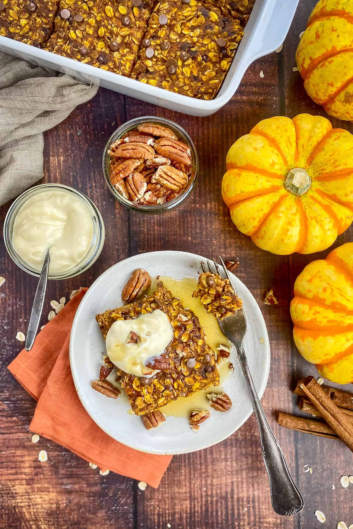 Baked pumpkin oats in a dish, three pumpkins, and a plate with a square of baked oats.