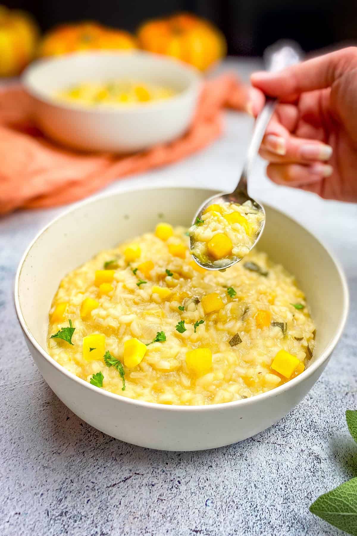 Hand picking up a spoonful of vegan pumpkin risotto.