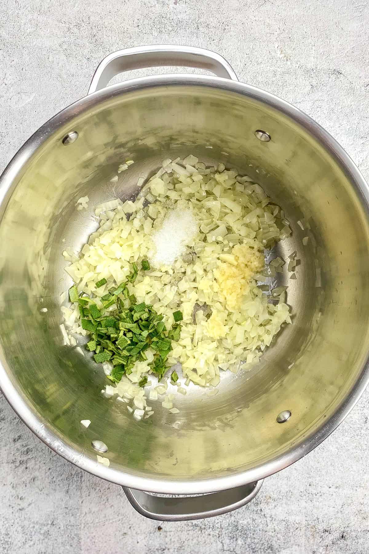 Onions, garlic, salt, and sage in a pot.
