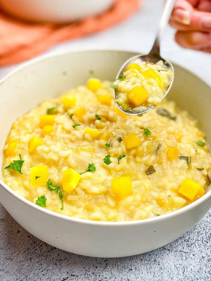Closeup of hand picking up a spoonful of vegan pumpkin risotto.