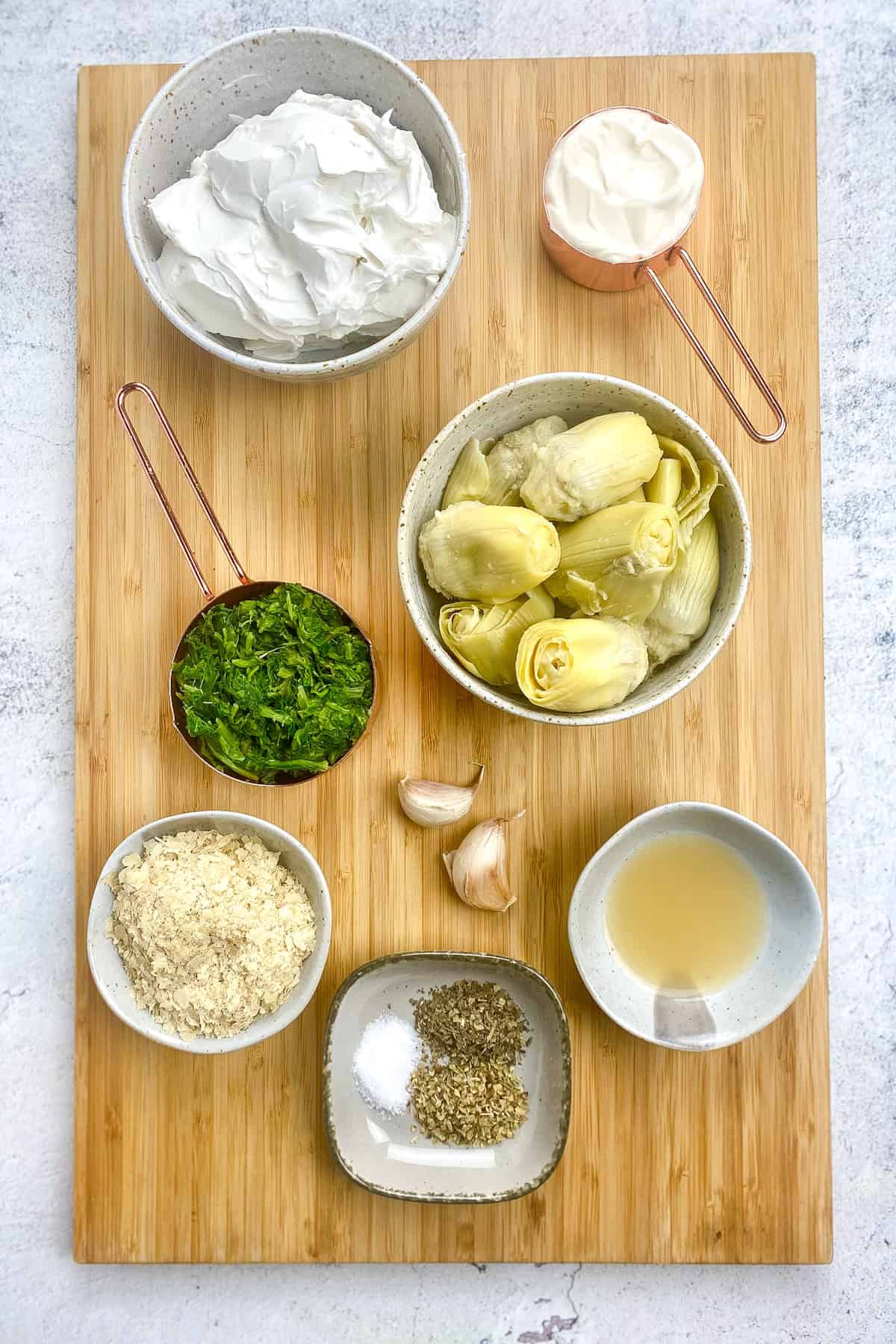 Ingredients for spinach-artichoke dip on a cutting board.