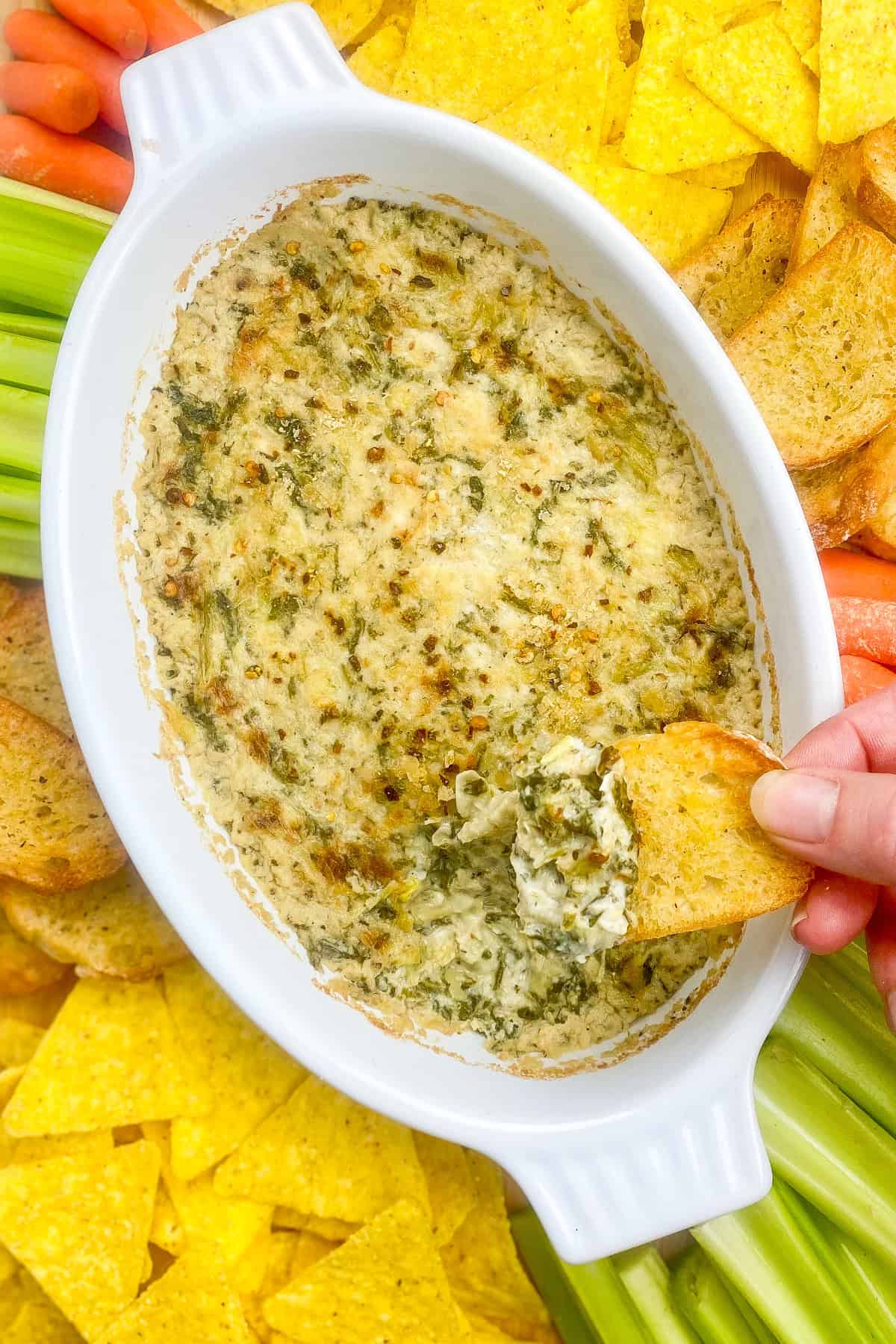 Holding holding a piece of toast that was dipping into the spinach artichoke dip.