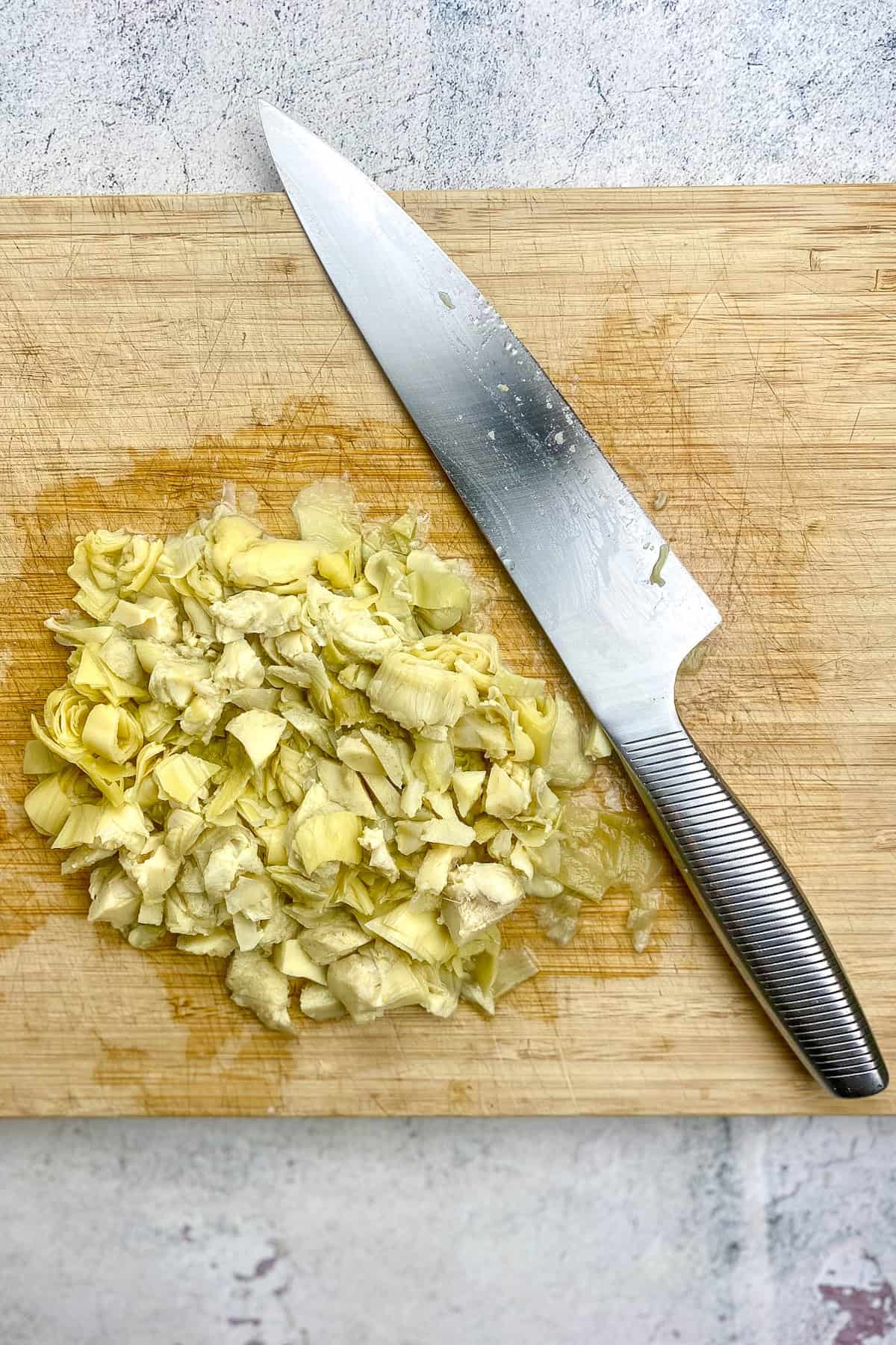 Roughly chopped artichoke hearts on a cutting board.