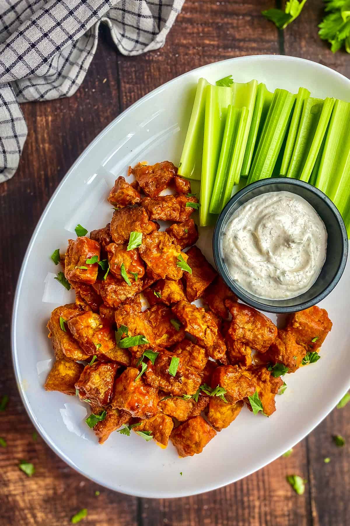 Buffalo tofu on a plate with sauce and celery.